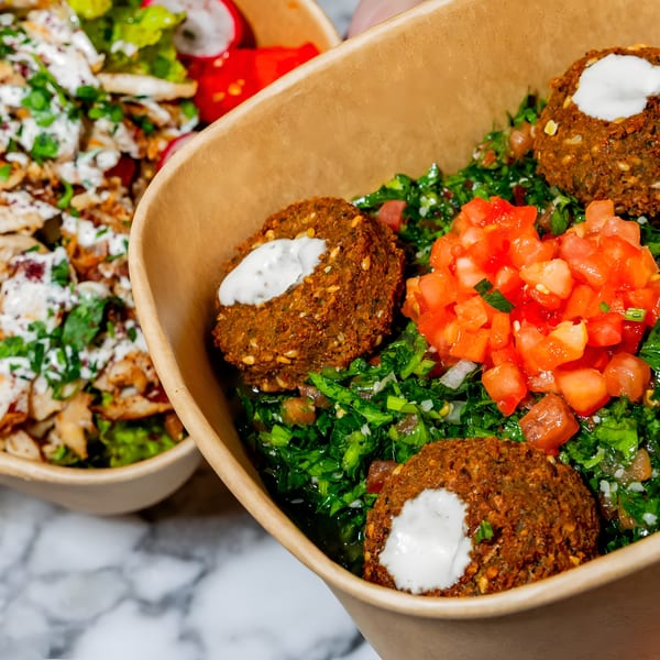 Two bowls of Middle Eastern food, one with falafel and tabbouleh, the other with chicken and salad.